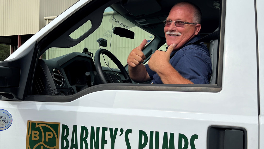Barney's Pumps employee sitting in company vehicle with two thumbs up